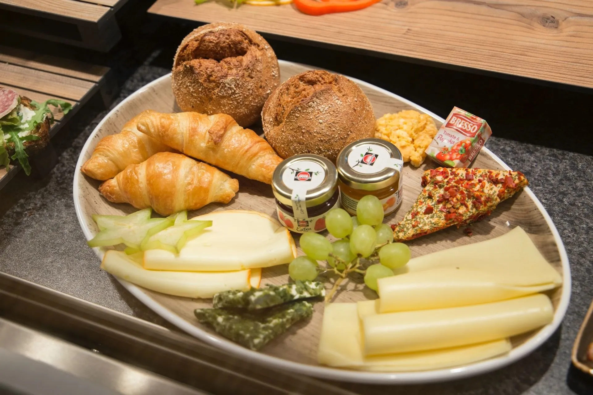 Frühstücksplatte mit Croissants, Brot, Käse und Trauben
