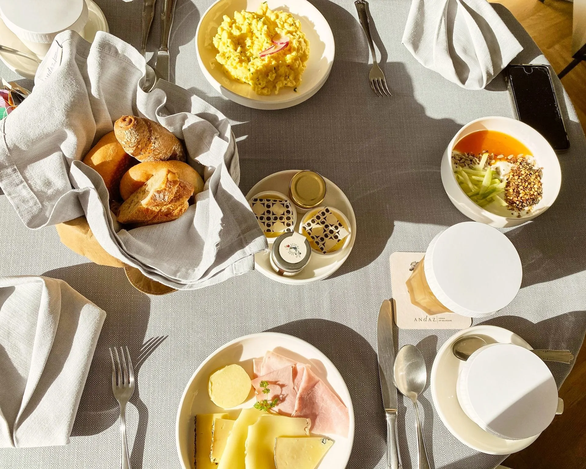 Gedeckter Frühstückstisch mit Brötchen, Rührei und Aufschnitt