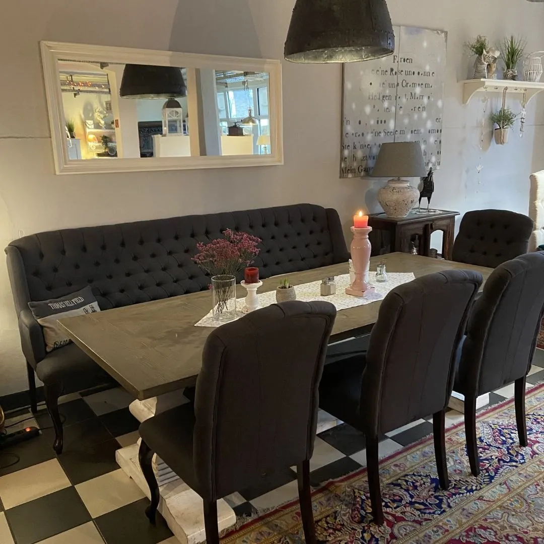 Tisch mit dunkler Polsterbank unter Wandspiegeln