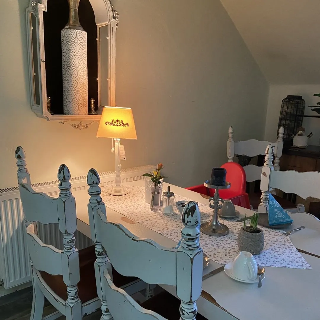Weiße Holzstühle und Tischlampe im Gastraum