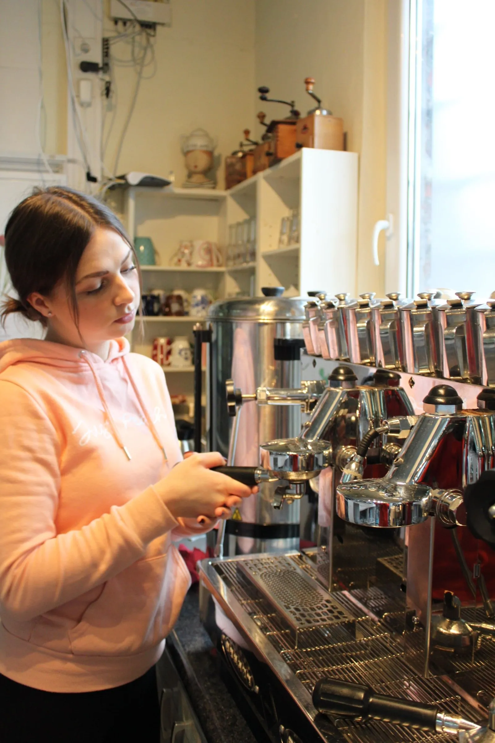 Mitarbeiterin bereitet Kaffee an der Siebträgermaschine zu