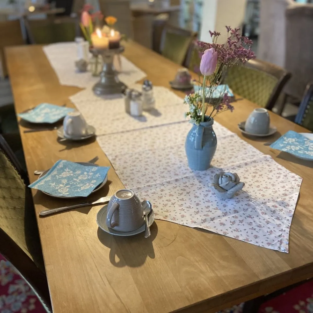 Gedeckter Holztisch mit Tassen und Blumenvase