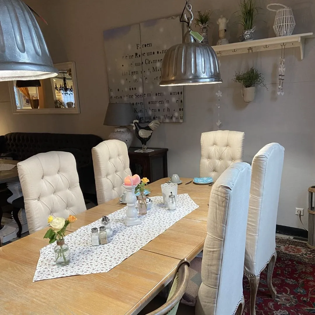 Gedeckte Tische mit hellen Polsterstühlen und Blumen