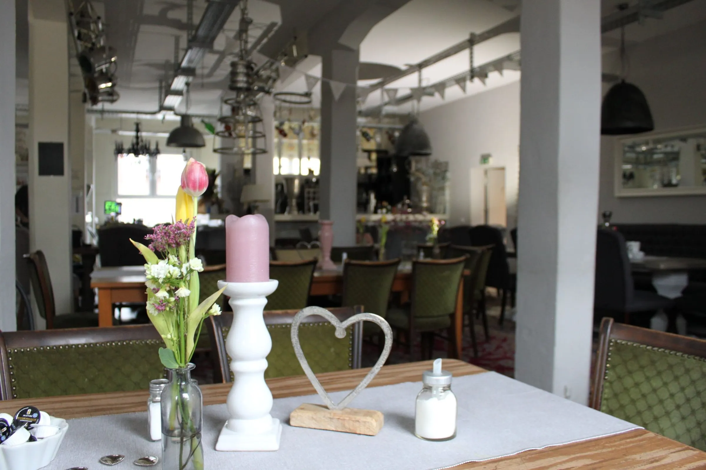 Gedeckter Tisch mit Tulpen, Kerze und Herz-Dekoration im Gastraum